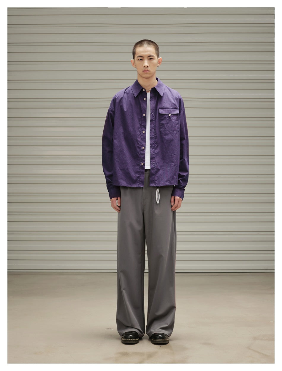 Model standing in gray wide-leg trousers with a purple button shirt, white tee and black shoes, front view
