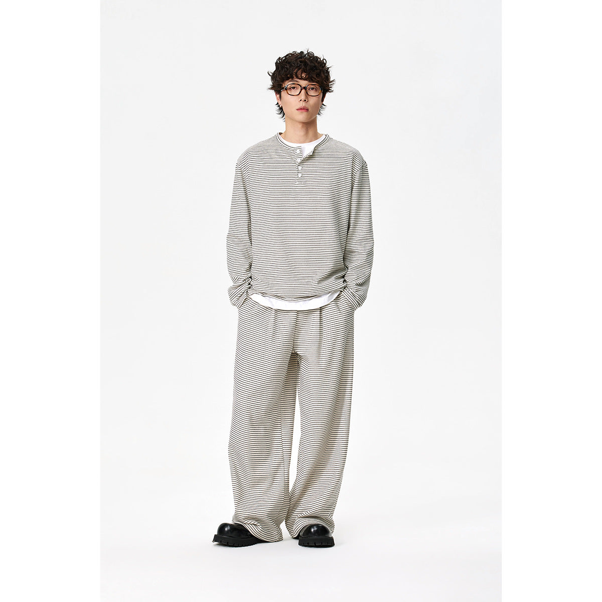 Full-length model wearing a cream thin-striped henley and matching loose trousers.