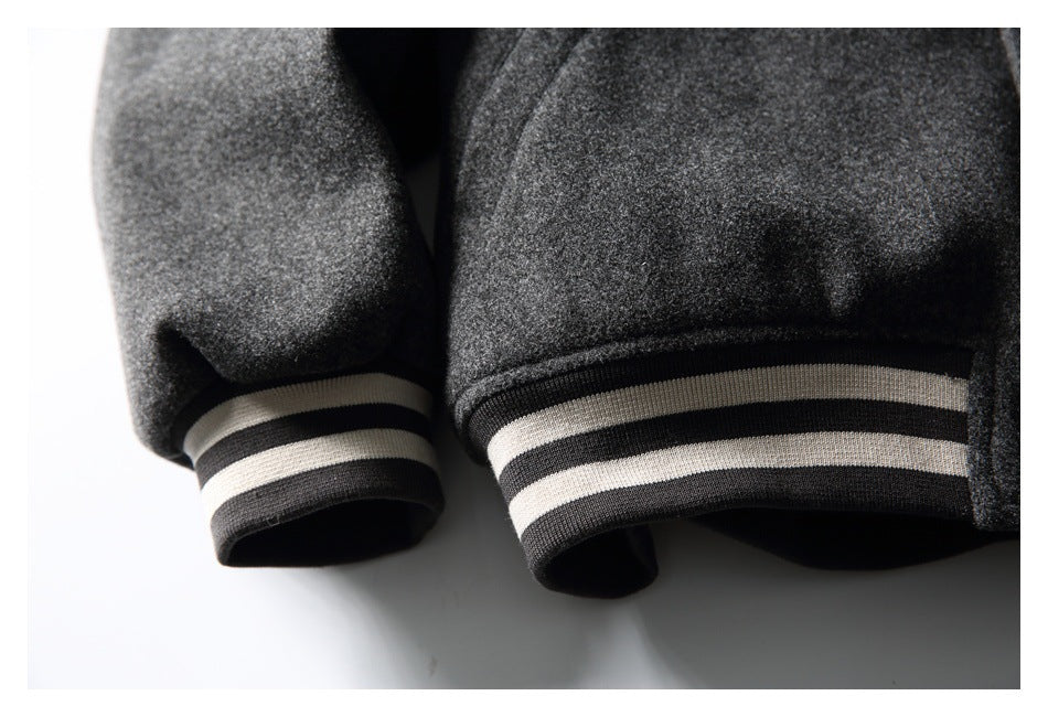 Close-up of the charcoal jacket's sleeve cuff and hem, both finished with black-and-cream horizontal stripes.
