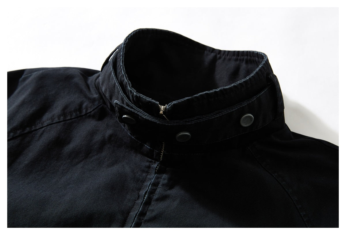 Close-up of a black jacket’s raised collar with a zipper and dark snap buttons.