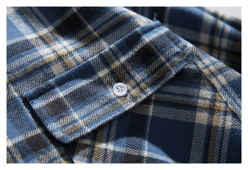 Close-up of a blue, cream and dark plaid shirt cuff with a white button.