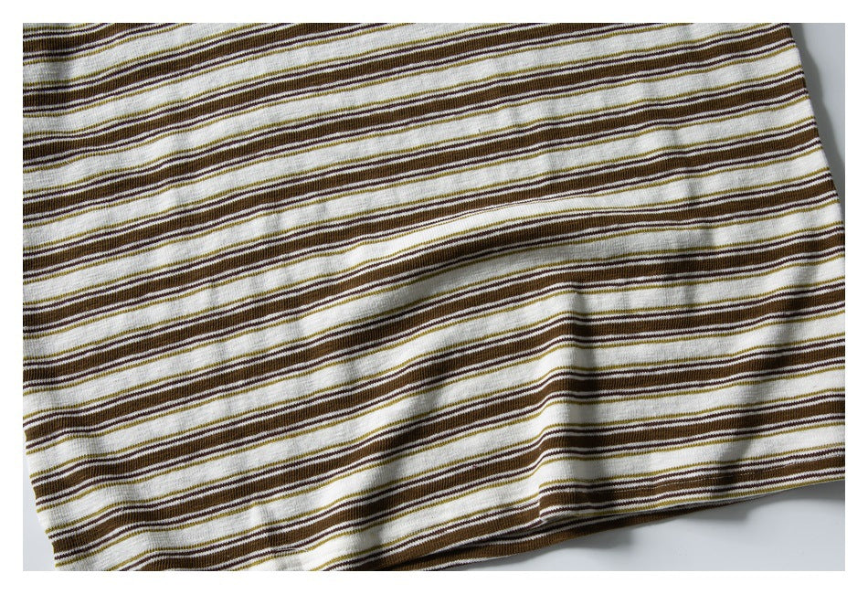 Close-up of cream fabric with narrow brown and olive horizontal stripes laid flat.