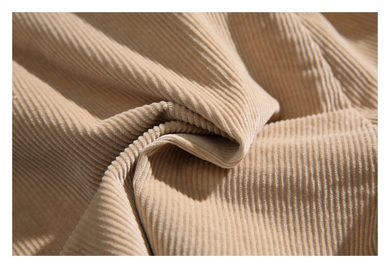 Close-up of beige ribbed corduroy fabric arranged in soft folds.