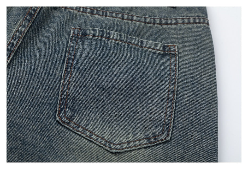 Close-up of a back pocket with brown stitching on faded blue-gray jeans.