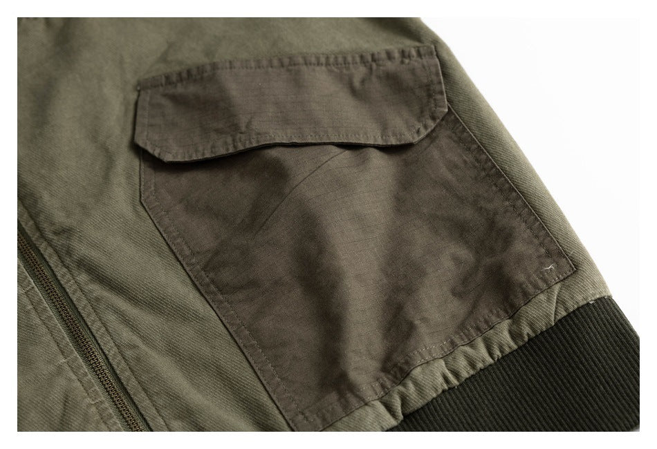 Close-up of an olive jacket's flap pocket, zipper edge, and dark ribbed trim.