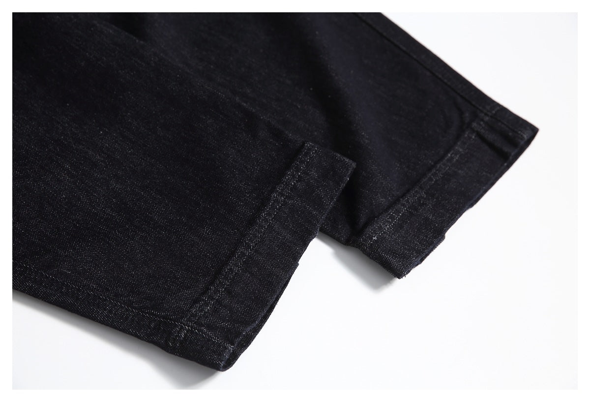 Close-up of the stitched hem and folded edge of black jeans.