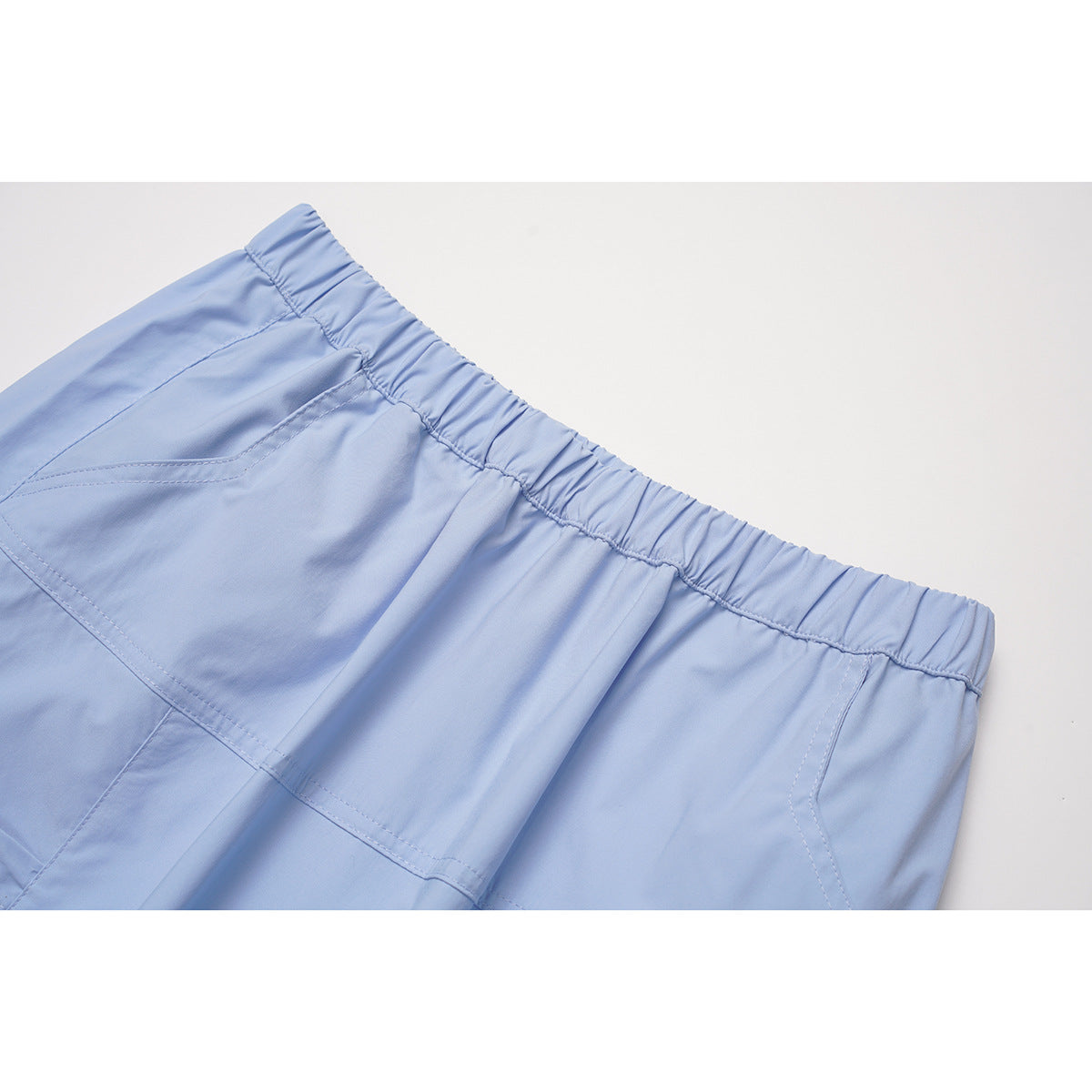 Close-up of a light blue skirt's gathered elastic waistband and stitched panel seams.