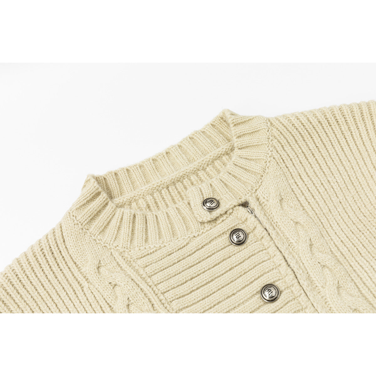 Close-up of an ivory cable-knit cardigan collar and button placket with round metallic buttons.