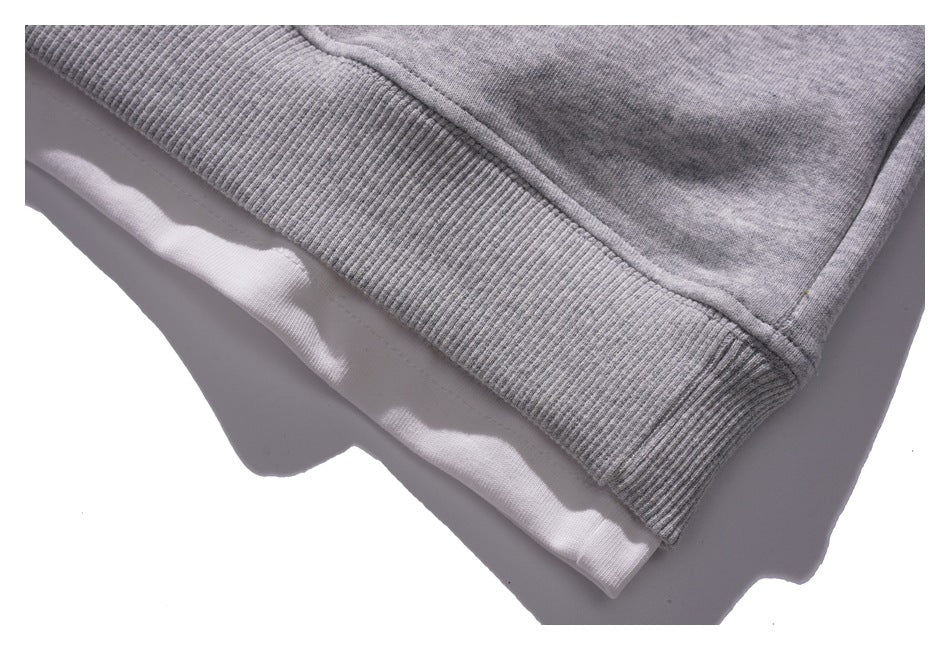 Close-up of the gray sweatshirt's ribbed hem and layered white fabric beneath it.
