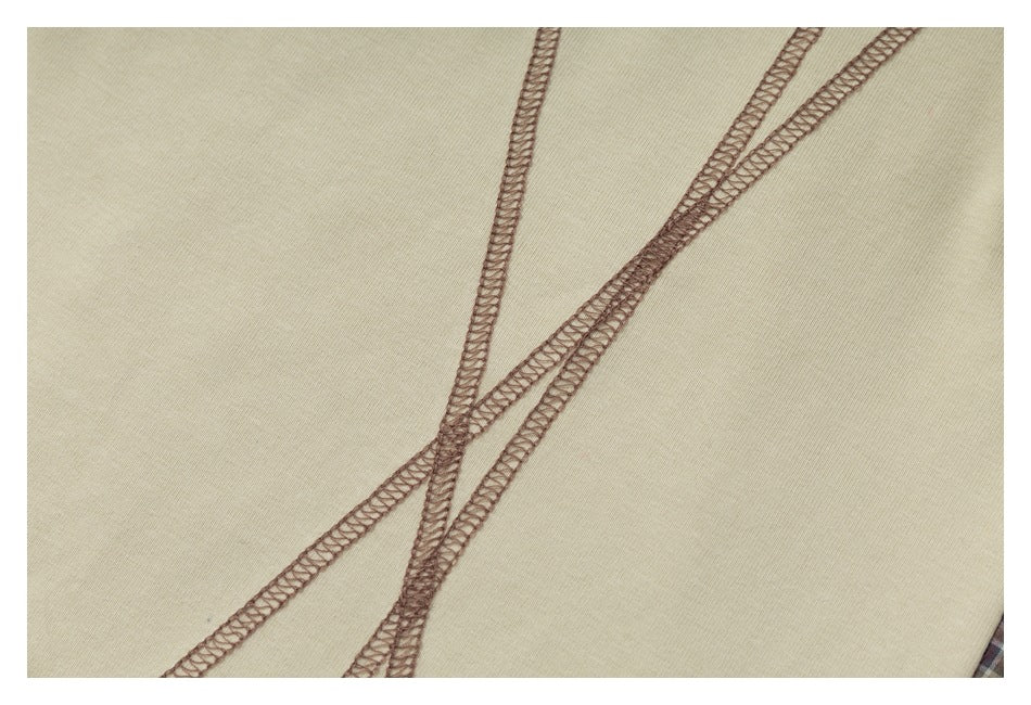 Close-up of intersecting brown overlock seams on cream fabric.