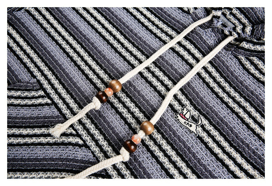 Close-up of cream braided drawstrings with wooden beads and a small animal patch on a gray striped pullover.