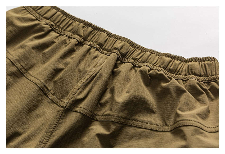 Close-up of olive-brown shorts showing the gathered elastic waistband and curved rear yoke seam.