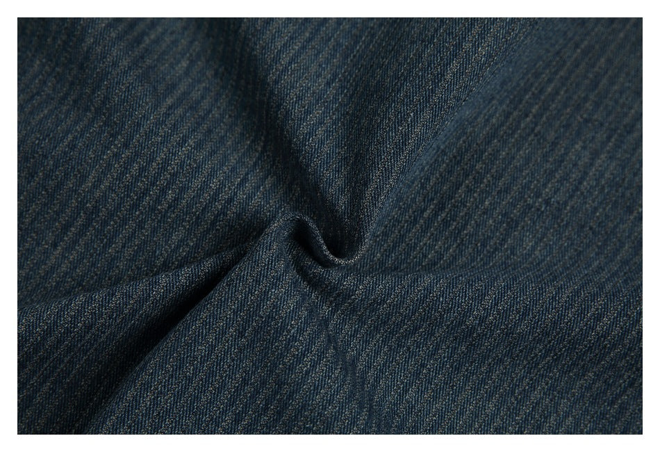 Close-up of dark blue denim fabric, showing its diagonal weave and textured surface.
