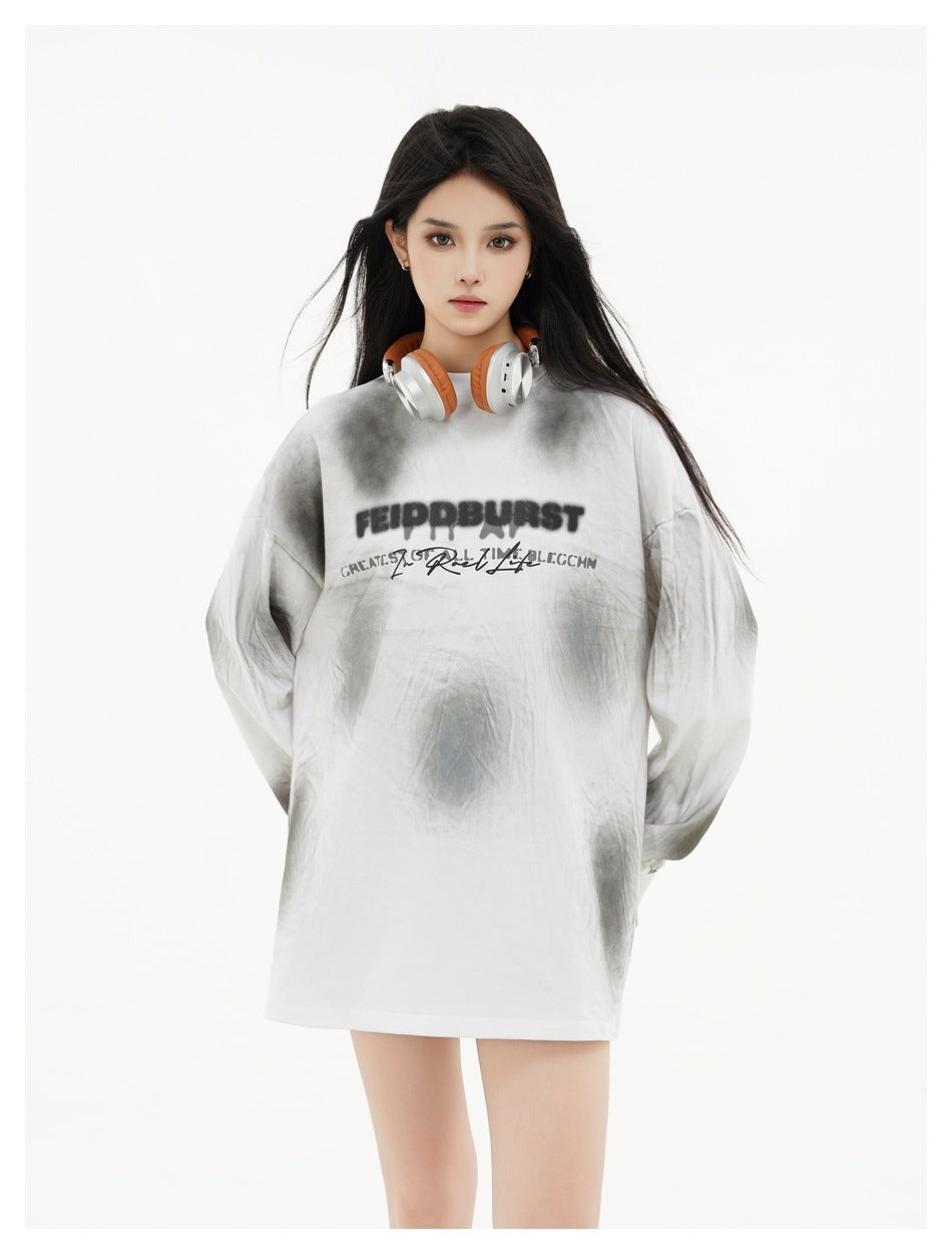 Model wearing an oversized white and gray tie-dye long-sleeve shirt with black chest lettering.