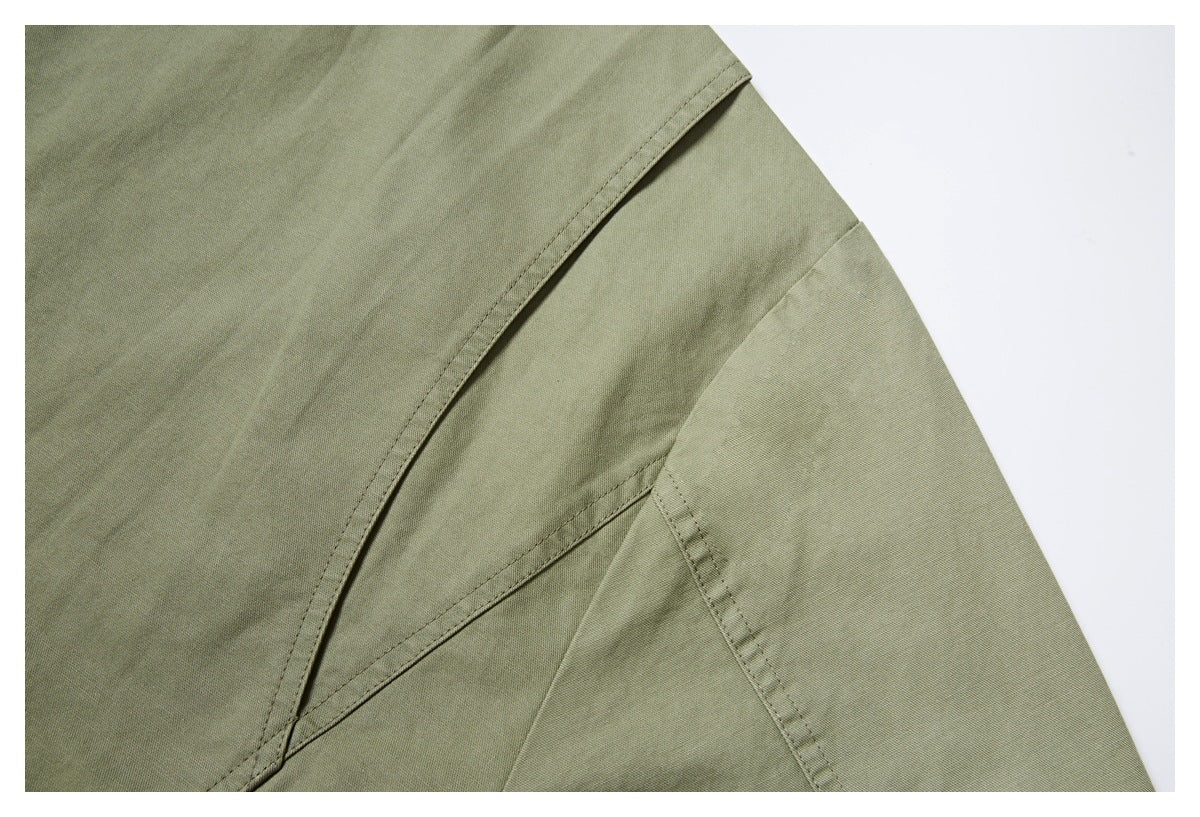 Close-up of olive garment panel and sleeve seams with visible topstitching.