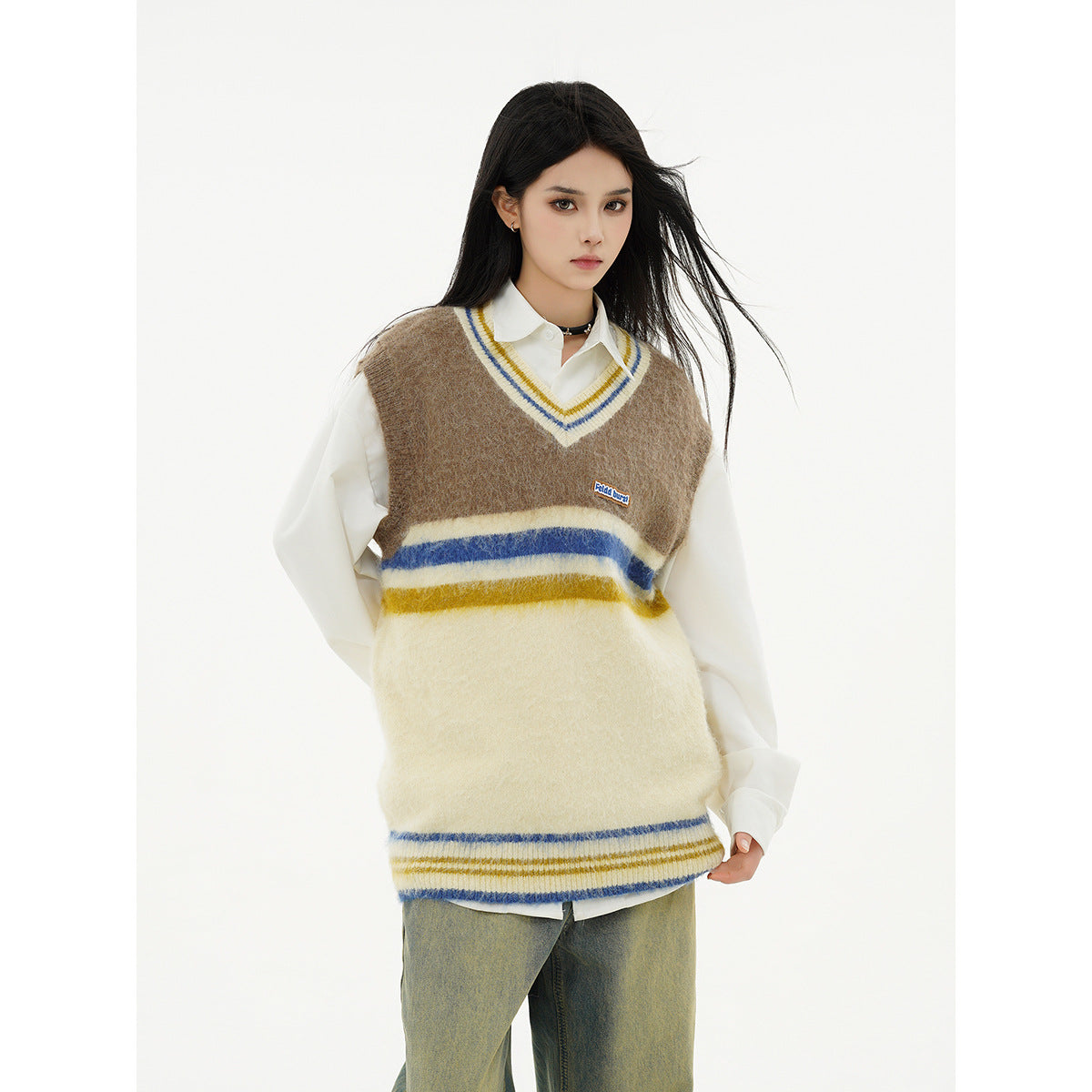 Closer front view of a model in a brown and cream striped V-neck sweater vest layered over a white shirt.