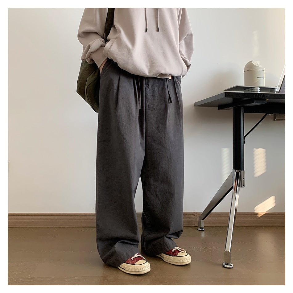Cropped outfit photo of a person wearing charcoal wide-leg drawstring trousers and sneakers.