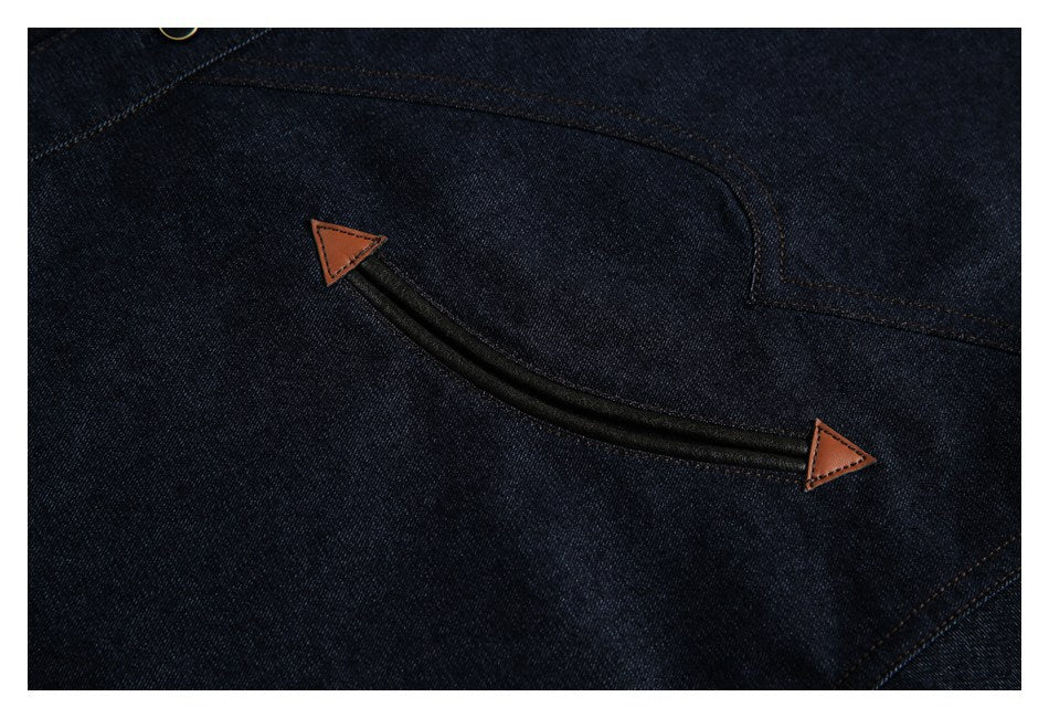 Close-up of dark indigo denim with a curved black trim detail and brown triangular tabs at both ends.