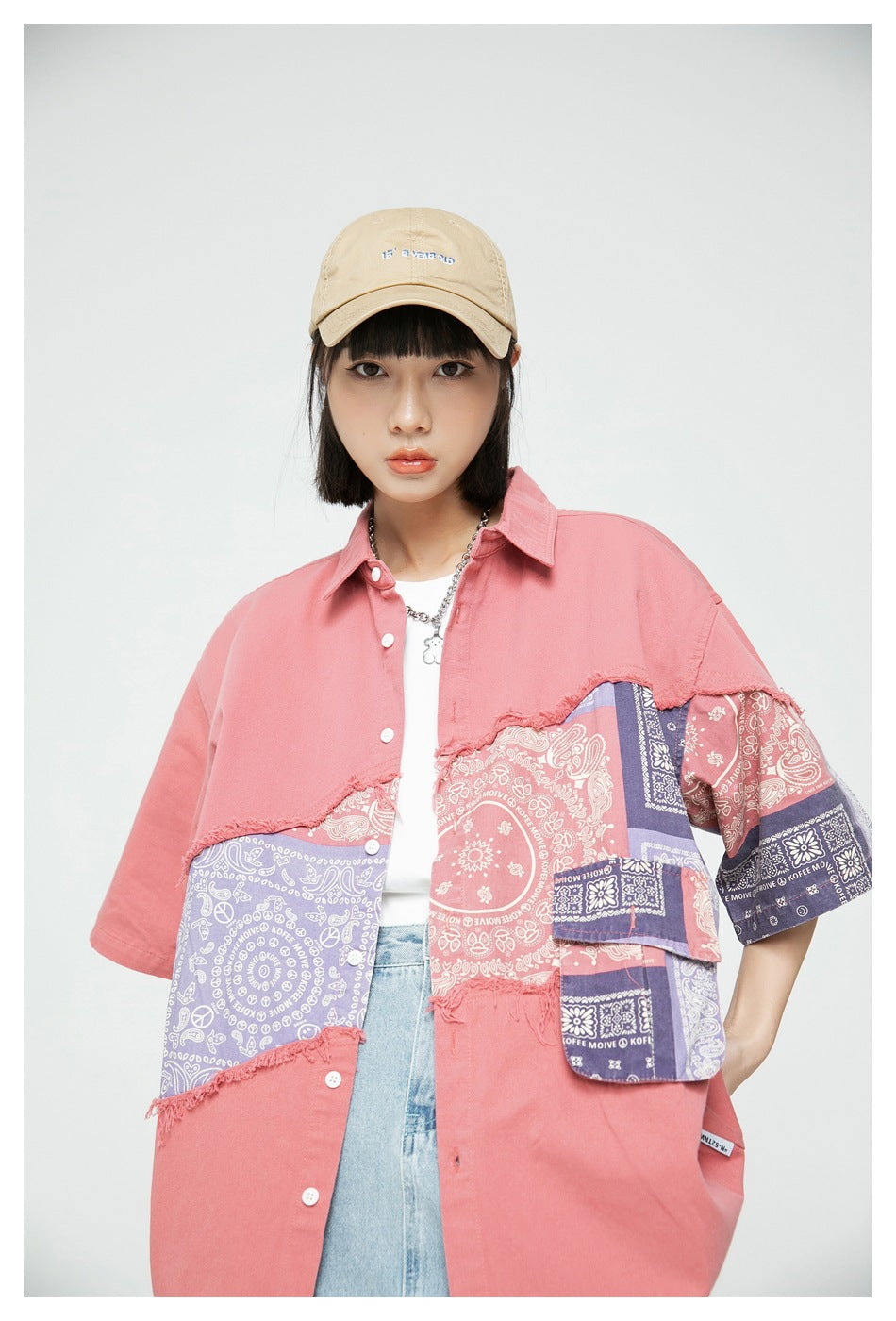 Model wearing a pink oversized shirt with frayed seams and pink, lavender, and navy bandana-print panels.