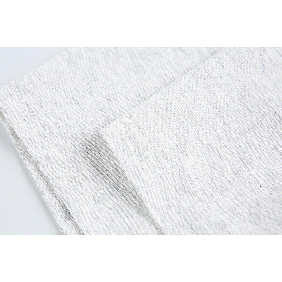 Close-up of light gray marled T-shirt fabric and stitched seam construction.