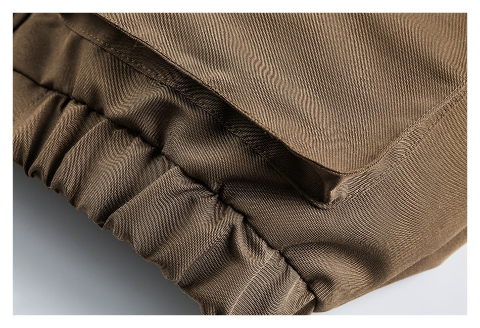 Close-up of brown fabric, a stitched flap edge, and a gathered elastic section.