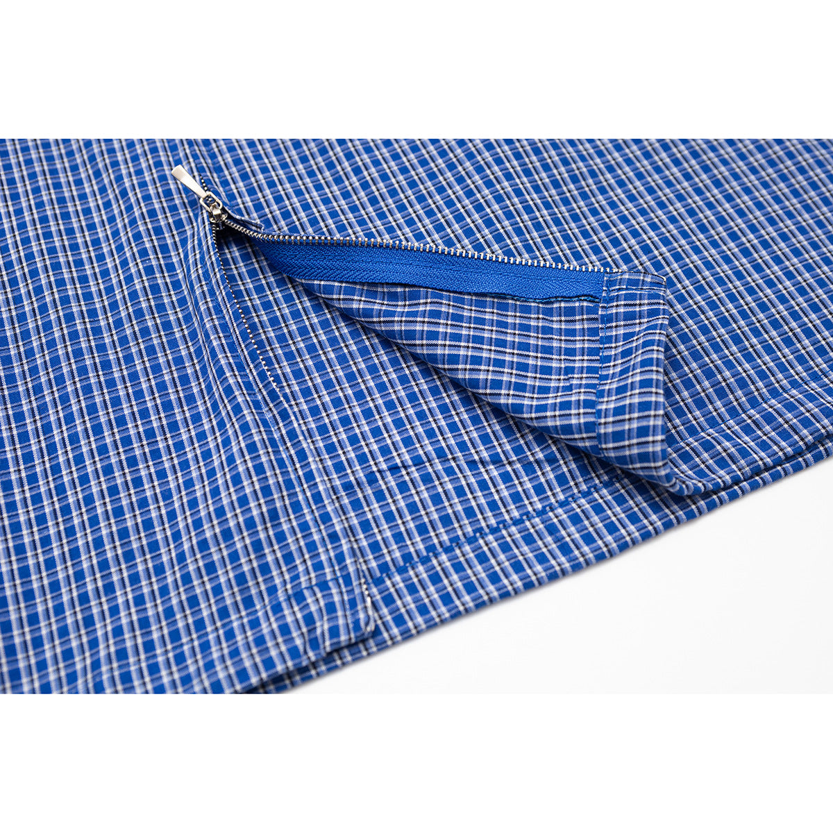 Close-up of a blue plaid shirt with a partly open zipper pocket and blue lining.