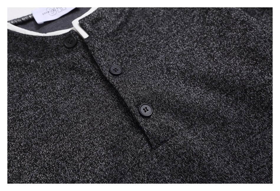 Close-up of a charcoal marled knit top with a white-trimmed neckline and dark buttons.