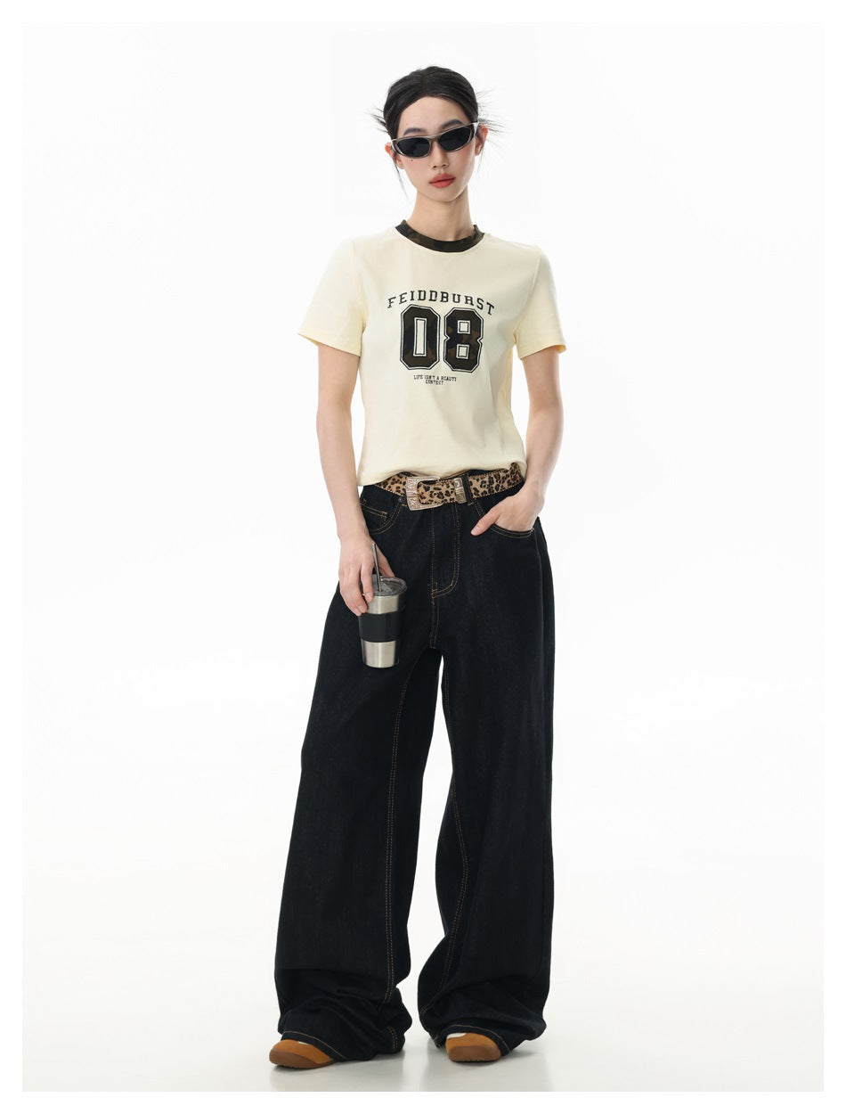 Model wearing beige 08 graphic tee with camo neckband, leopard belt, wide-leg dark jeans and sunglasses