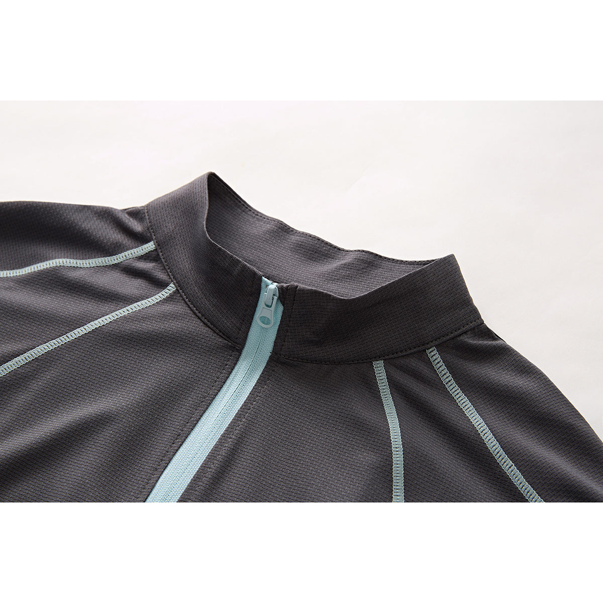 Close-up of a charcoal short-sleeve top’s stand collar, pale blue quarter zipper and contrast seams.