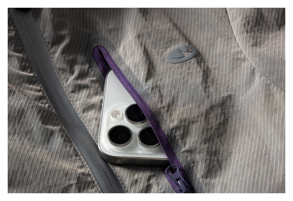 Close-up of a purple-trimmed chest pocket on the gray vest, with a phone tucked inside.