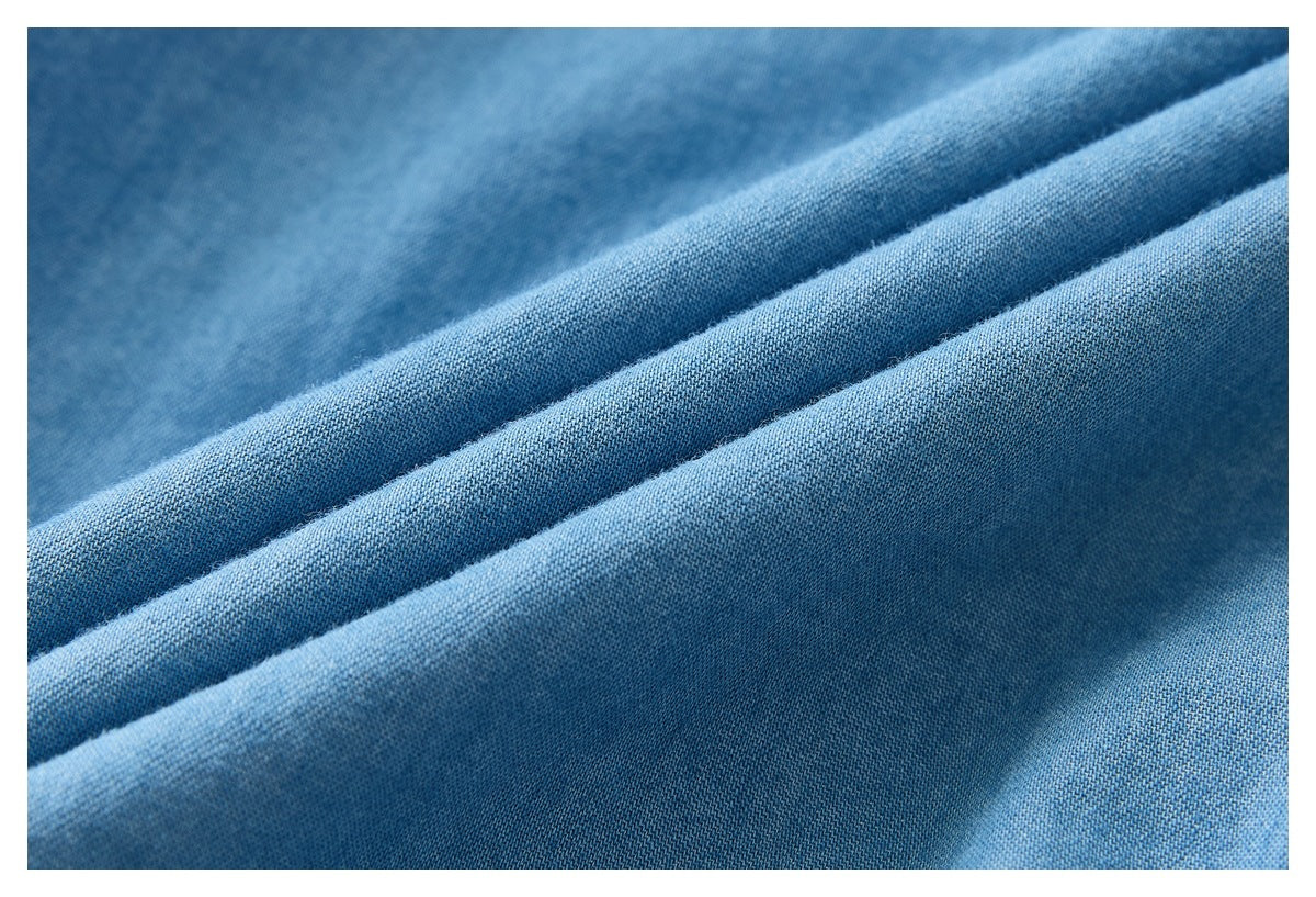Macro view of light blue fabric folded to show its woven surface and texture.