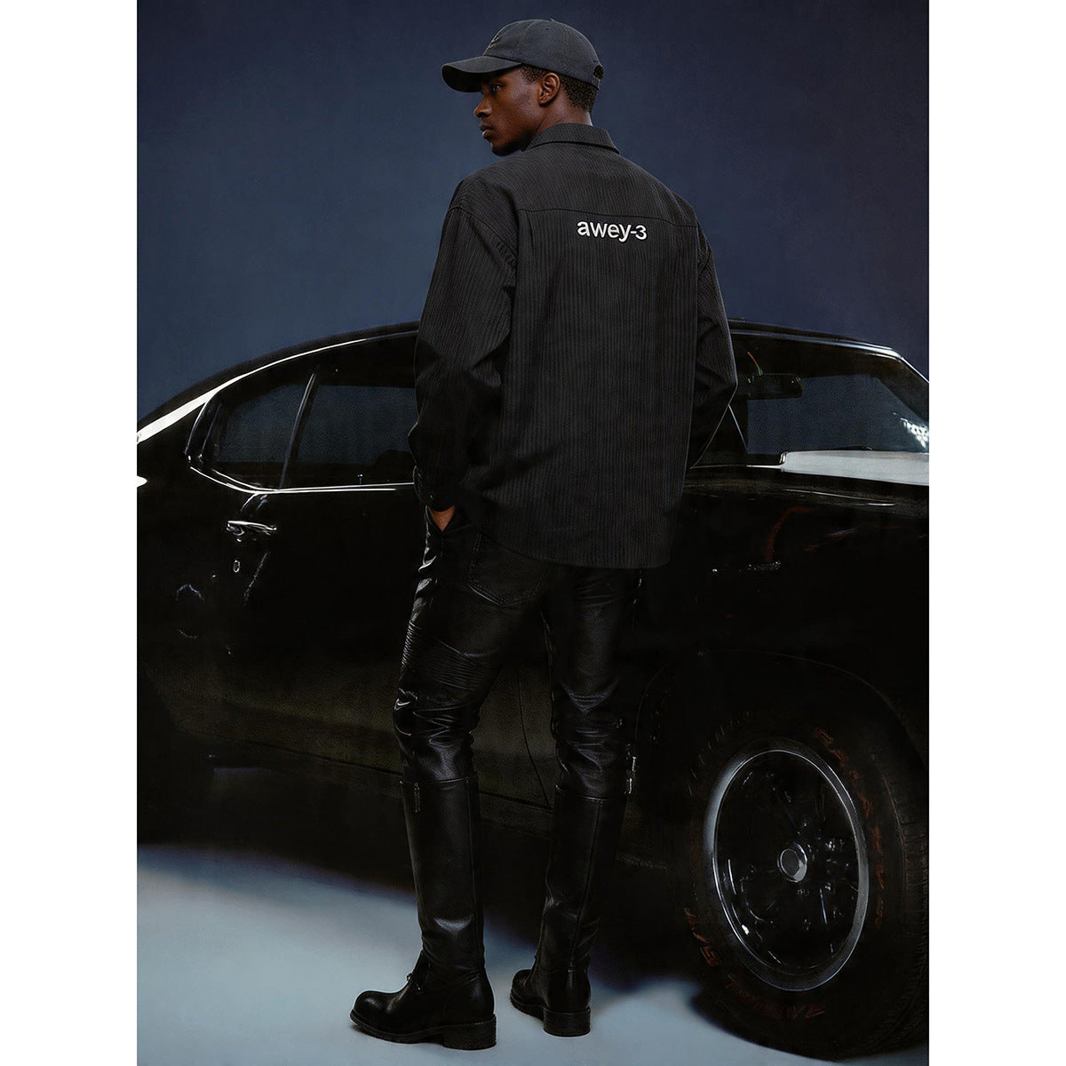 Model seen from behind wearing a black long-sleeve shirt with white lettering across the back.