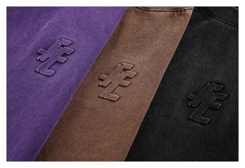 Close-up of raised tonal emblems on purple, brown, and black shirt fabric.