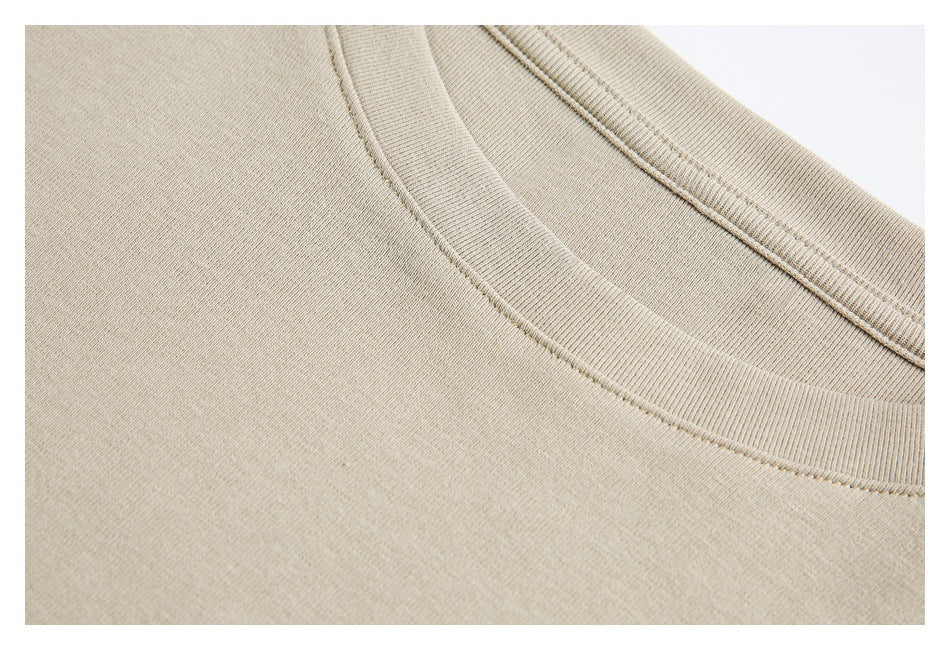Extreme close-up of beige knit fabric, ribbed crew collar, and seam stitching.