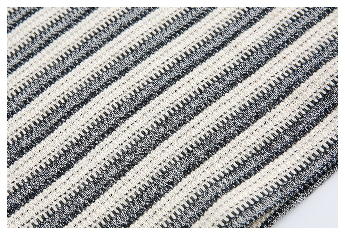 Close-up of black and ivory striped knit fabric and a finished garment edge.