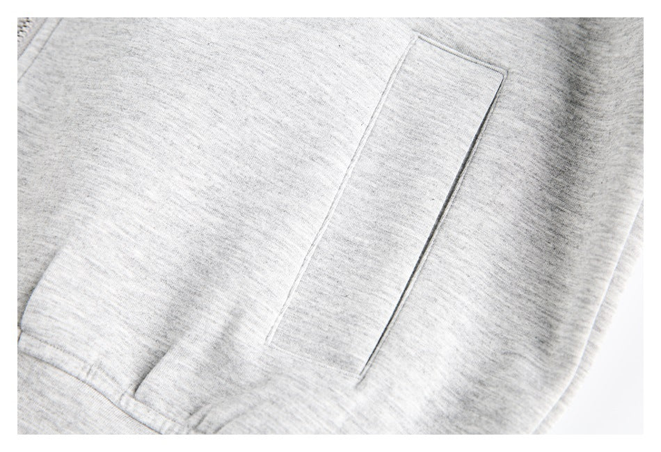 Close-up of a rectangular welt pocket on light gray heather hoodie fabric.
