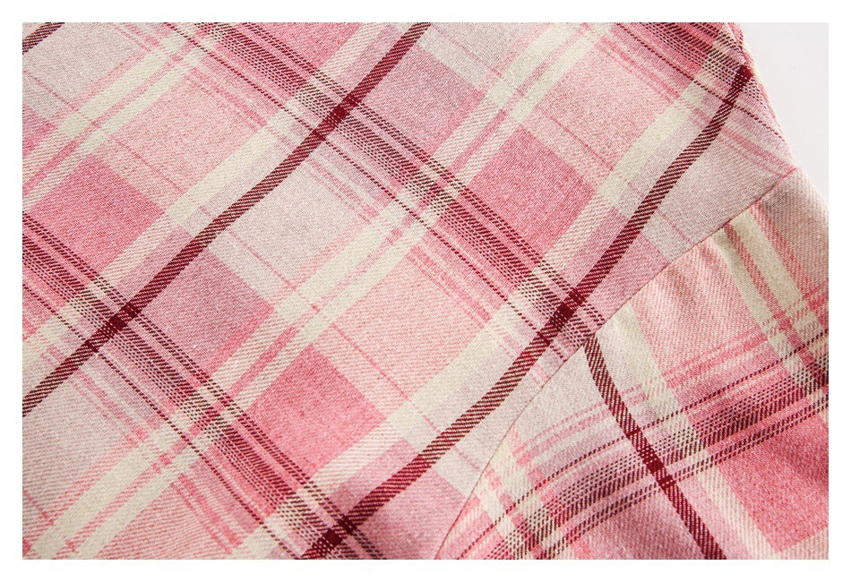 Close-up of pink, cream, and burgundy plaid fabric with a curved garment seam.