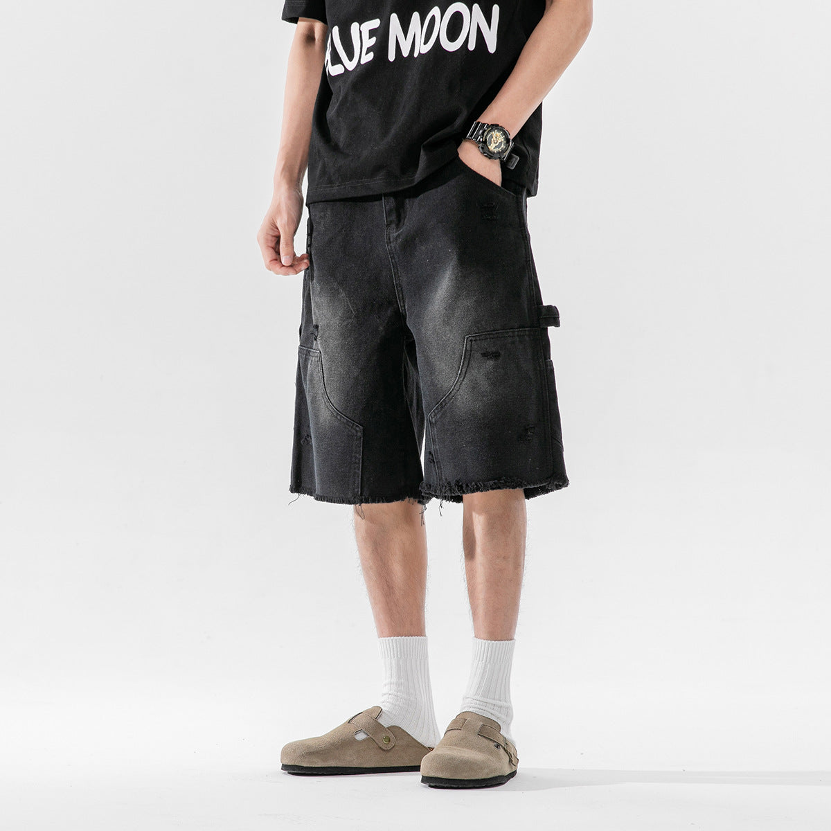 Model wearing black distressed cargo shorts with large patch pockets and frayed hems, front view.