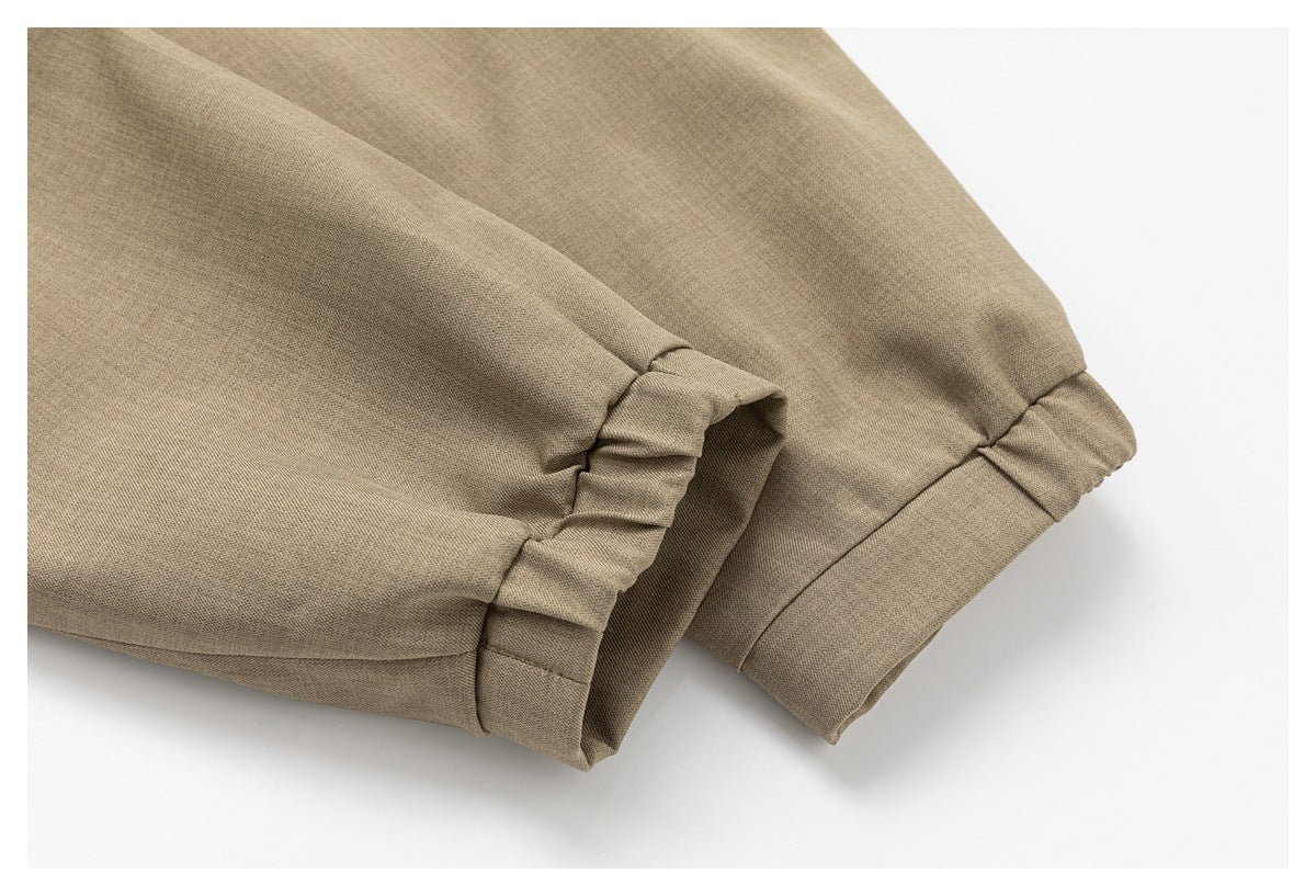 Close-up of taupe garment fabric showing two gathered, banded sleeve or leg openings.