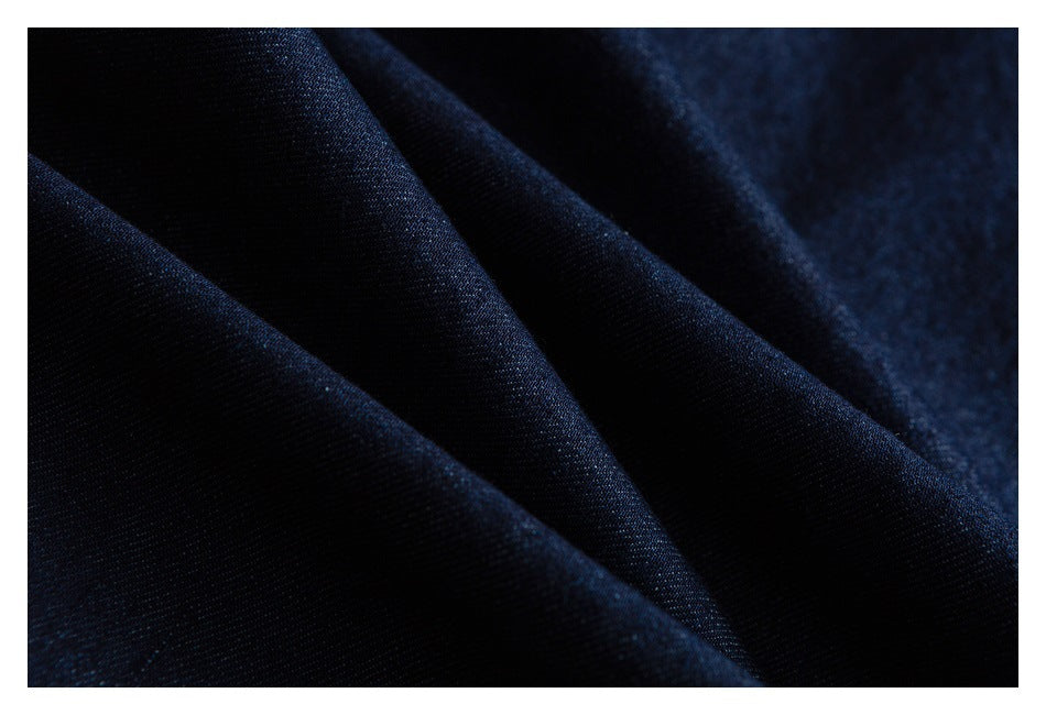 Macro view of dark indigo denim fabric folded to show its surface and texture.