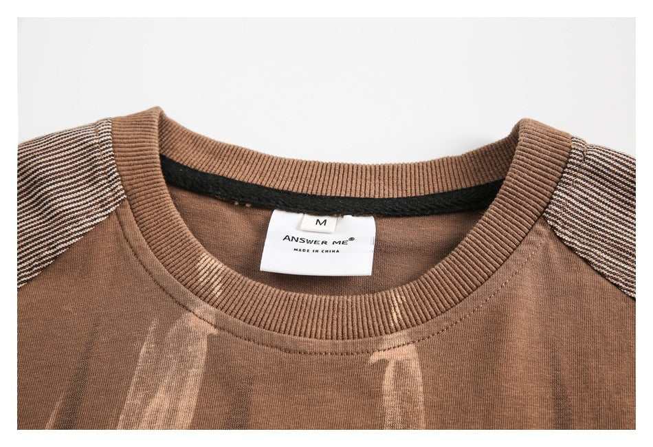 Close-up of the brown T-shirt's ribbed neckline, striped shoulders, and interior size and brand labels.