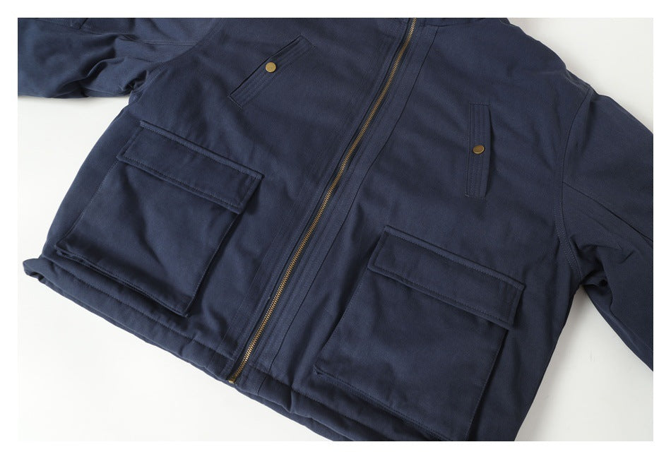 Cropped flat-lay front view of a navy jacket with brass zipper, snap details, and large flap pockets.