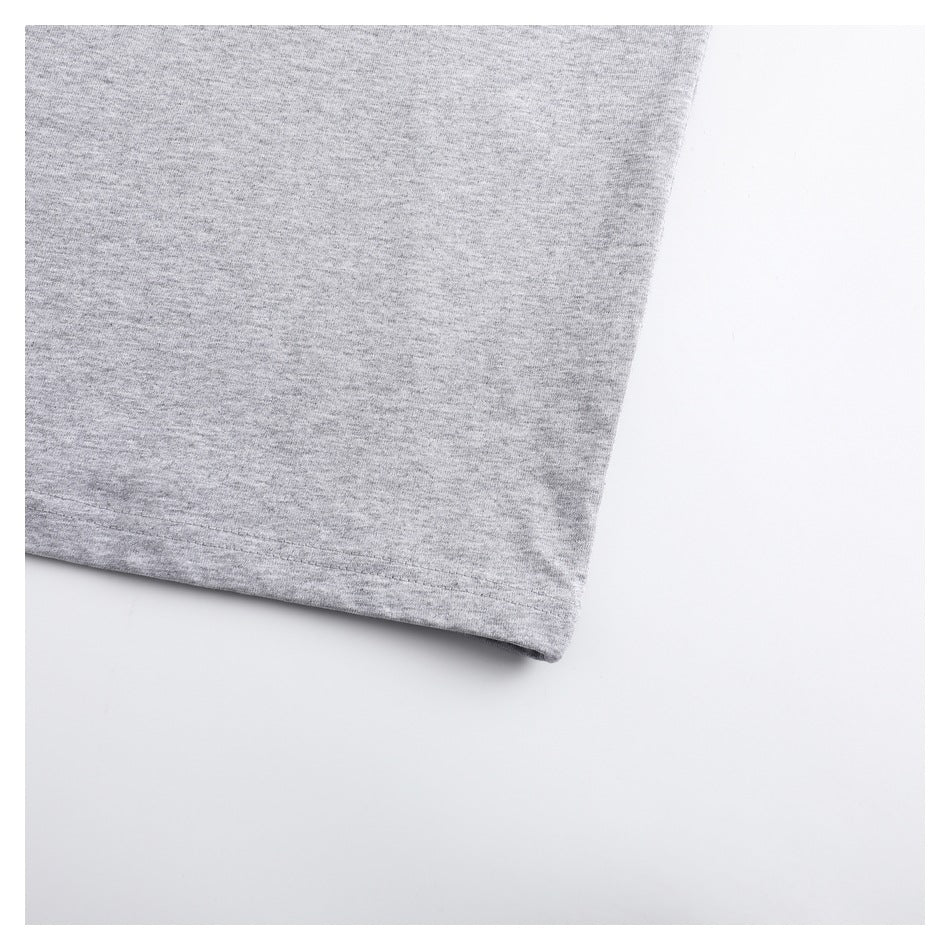 Close-up of the lower edge of a heather gray T-shirt against a white background.