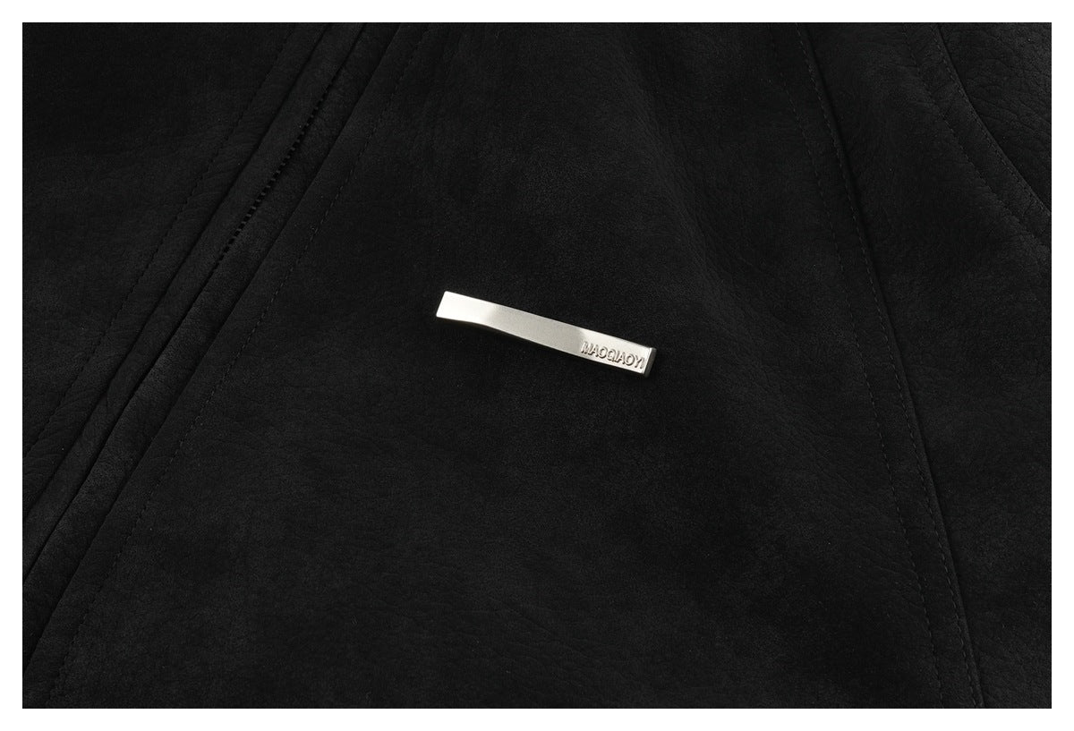 Close-up of a small silver-tone nameplate on the black jacket, between stitched panels.