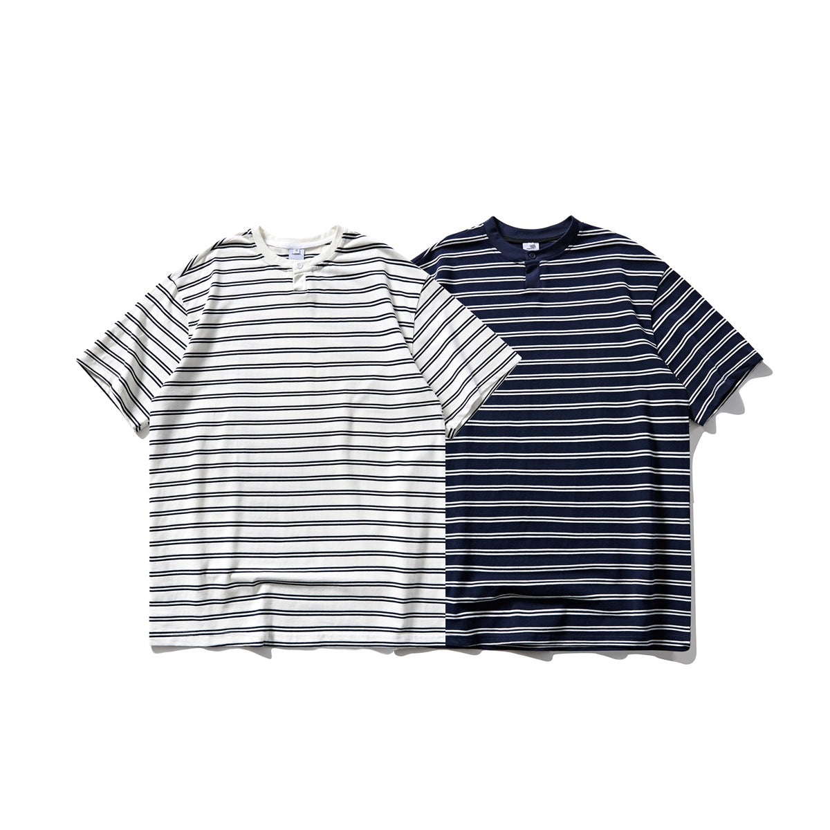 Front view of two short-sleeve striped button-placket T-shirts: ivory with navy stripes and navy with ivory stripes.