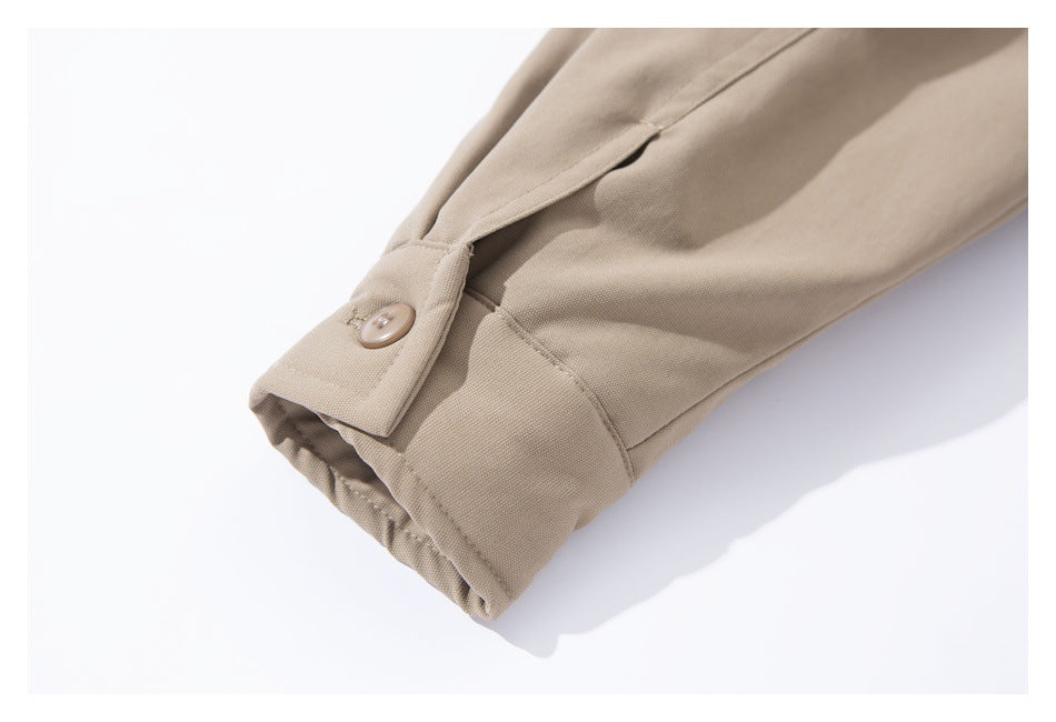 Close-up of a beige jacket sleeve cuff with a buttoned tab and gathered edge.