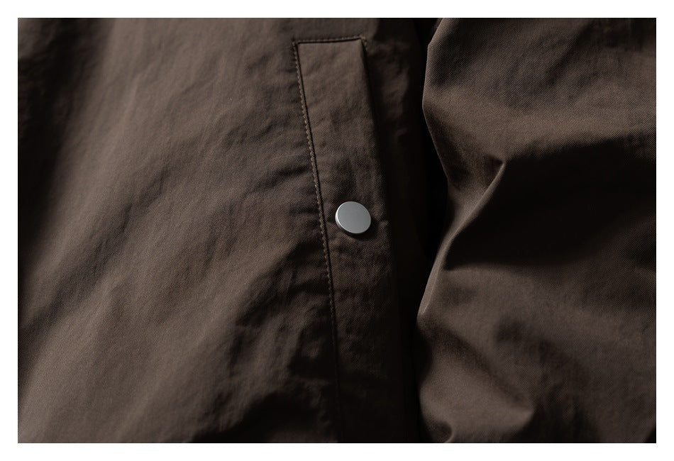 Close-up of a dark brown jacket placket with a silver snap fastener.