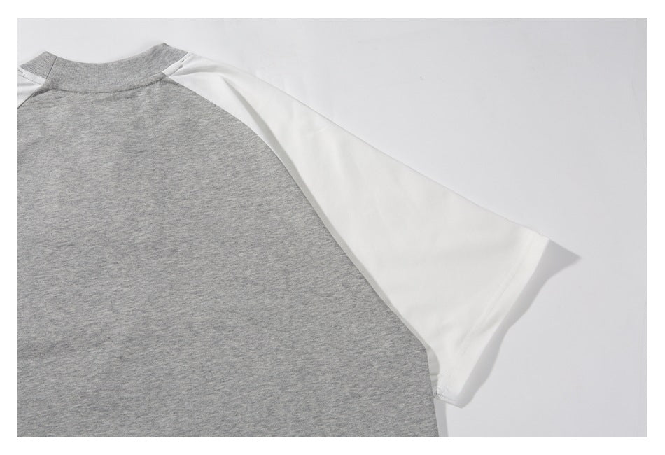 Close-up of a gray raglan shirt body with a white sleeve and ribbed neckline.