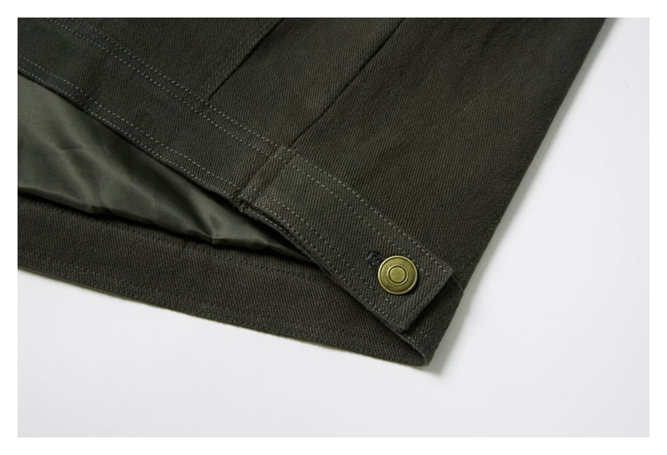 Close-up of a dark olive garment hem with a brass-colored snap, visible stitching, and inner lining.