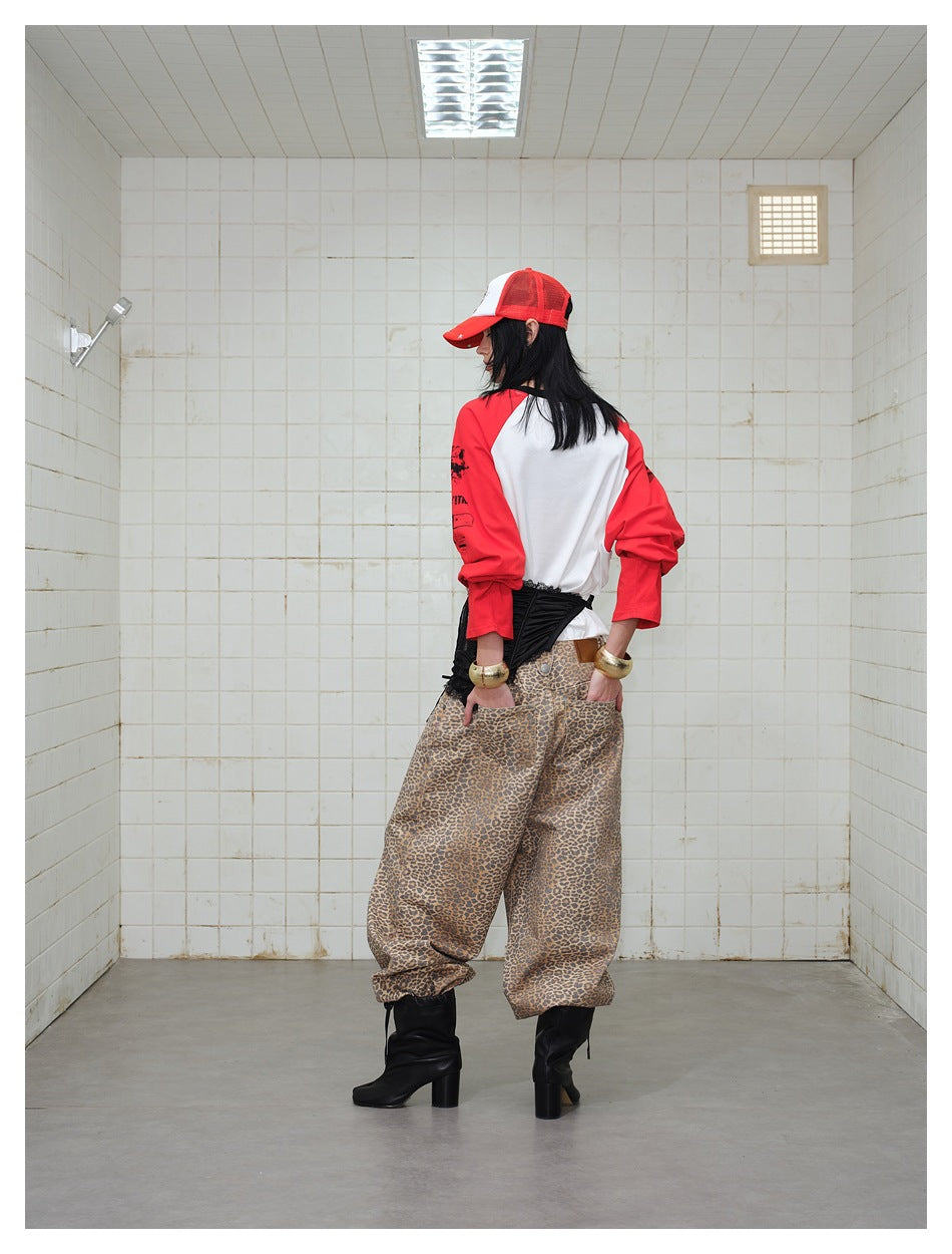 Rear view of a model wearing a white shirt with red sleeves, a black corset belt, and loose leopard-print pants.